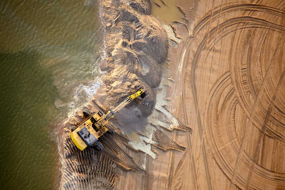 Aerial drone view of a large excavation site beside water