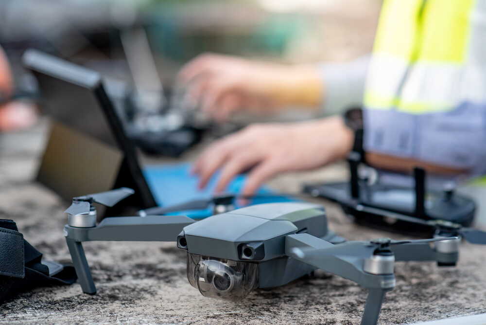 Close-up of a survey drone on site with operator controlling tablet